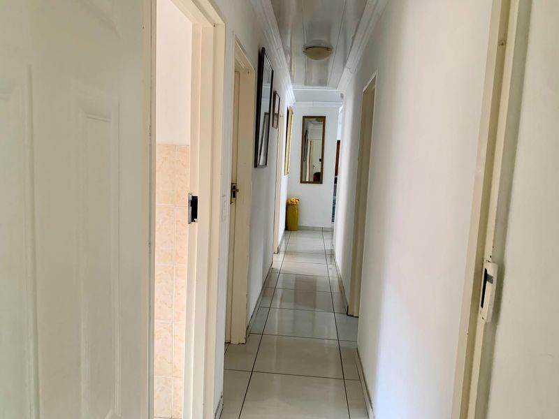 A clean, neutral hallway featuring tiled flooring and multiple doorways leading to adjacent rooms, providing a bright and functional transition space.