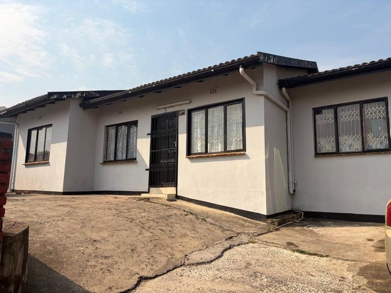Front elevation of a single-story house featuring a tiled roof, security gates, and a concrete driveway showing signs of wear.