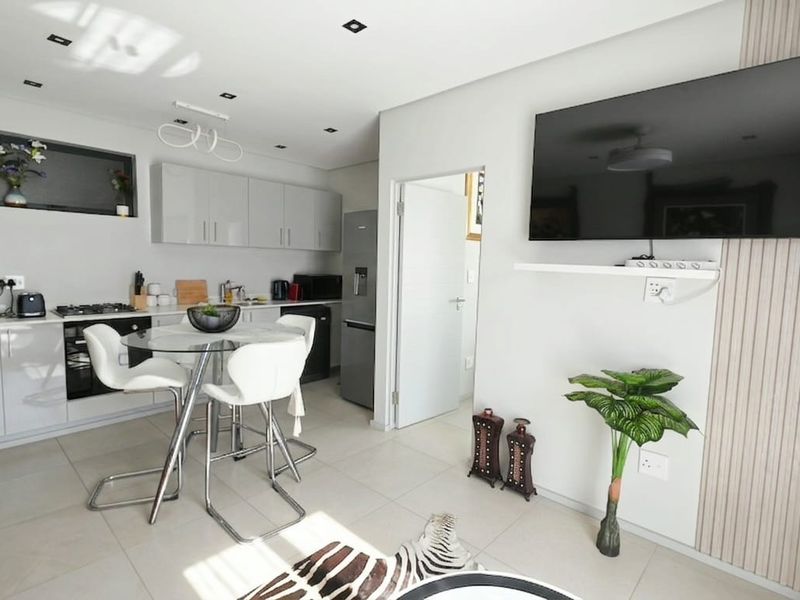 Modern open-plan living area featuring a sleek kitchen with built-in cabinetry, gas hob, and tiled flooring, seamlessly integrated with the lounge space.