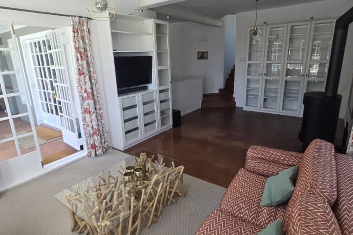 A bright living room featuring built-in cabinetry, a freestanding fireplace, and large glass-paned doors providing seamless access to the outdoor patio area.