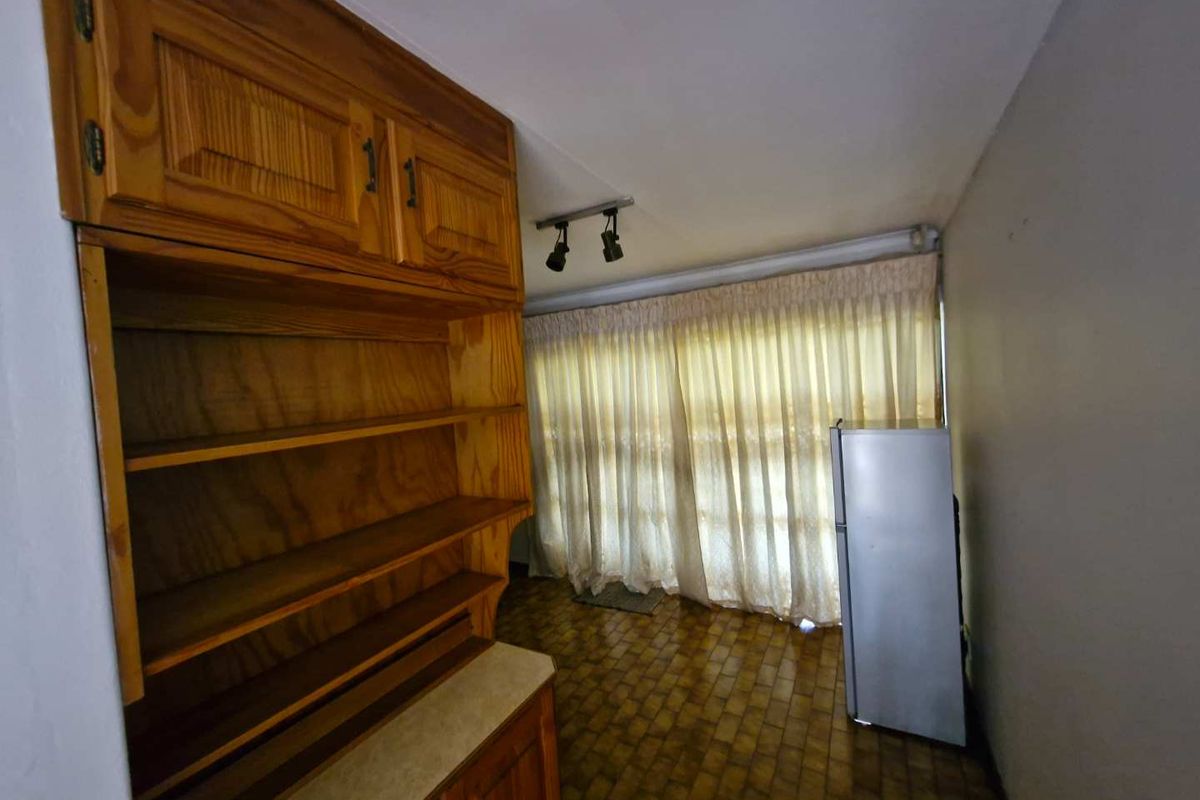 A dated kitchen area featuring wooden cabinetry, tiled flooring, and track lighting, offering potential for a modern renovation.