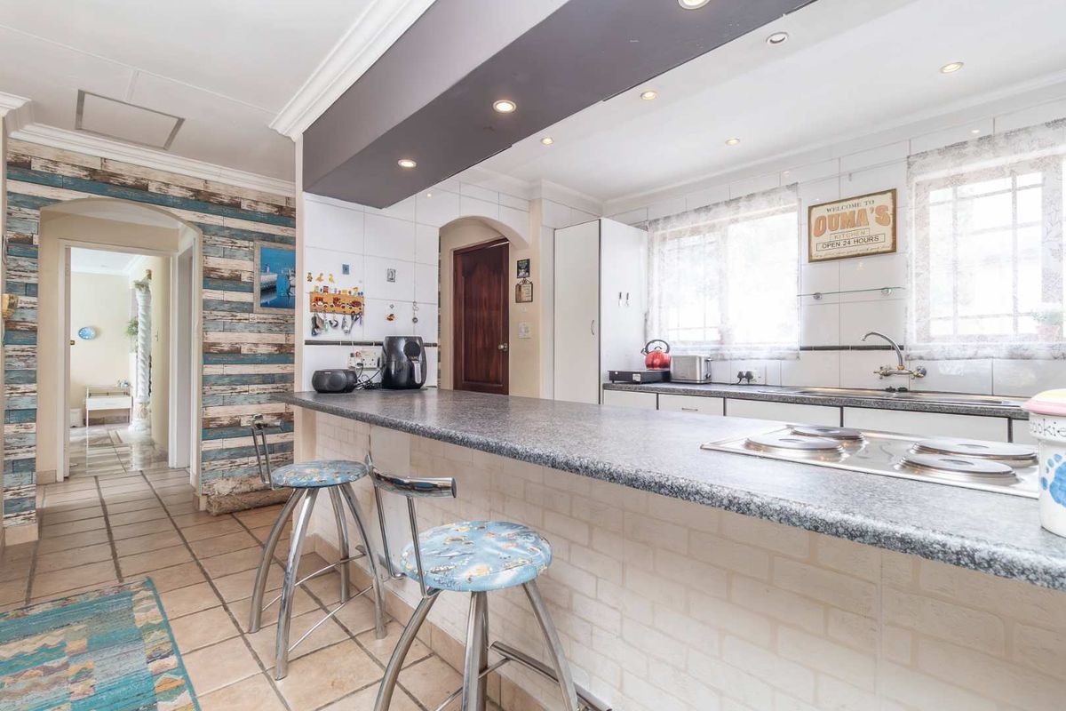 A functional kitchen featuring a breakfast bar, built-in hob, and tiled flooring, providing a practical space for meal preparation and casual dining.