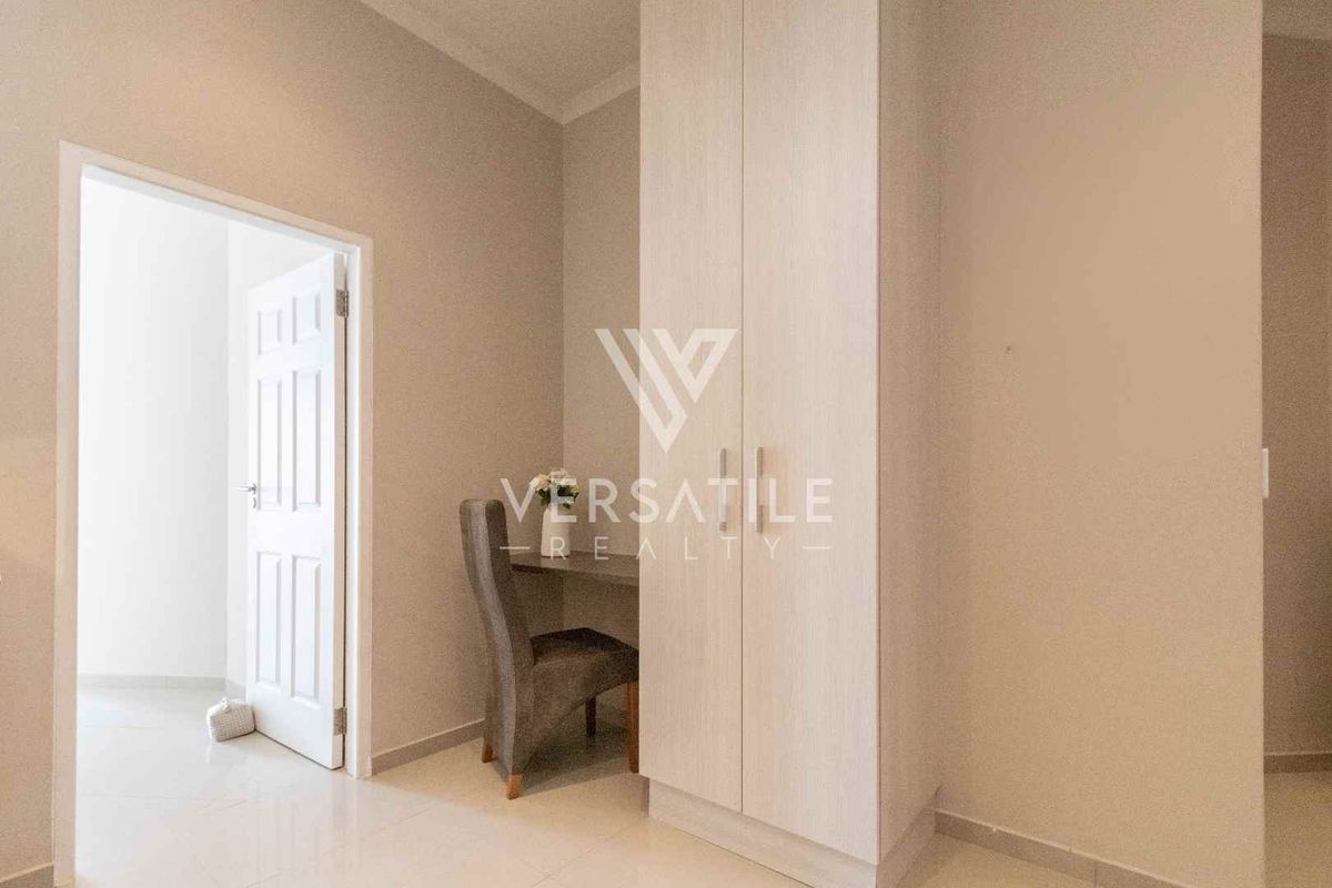 A bedroom featuring built-in cabinetry and a dedicated desk area with neutral finishes and tiled flooring.