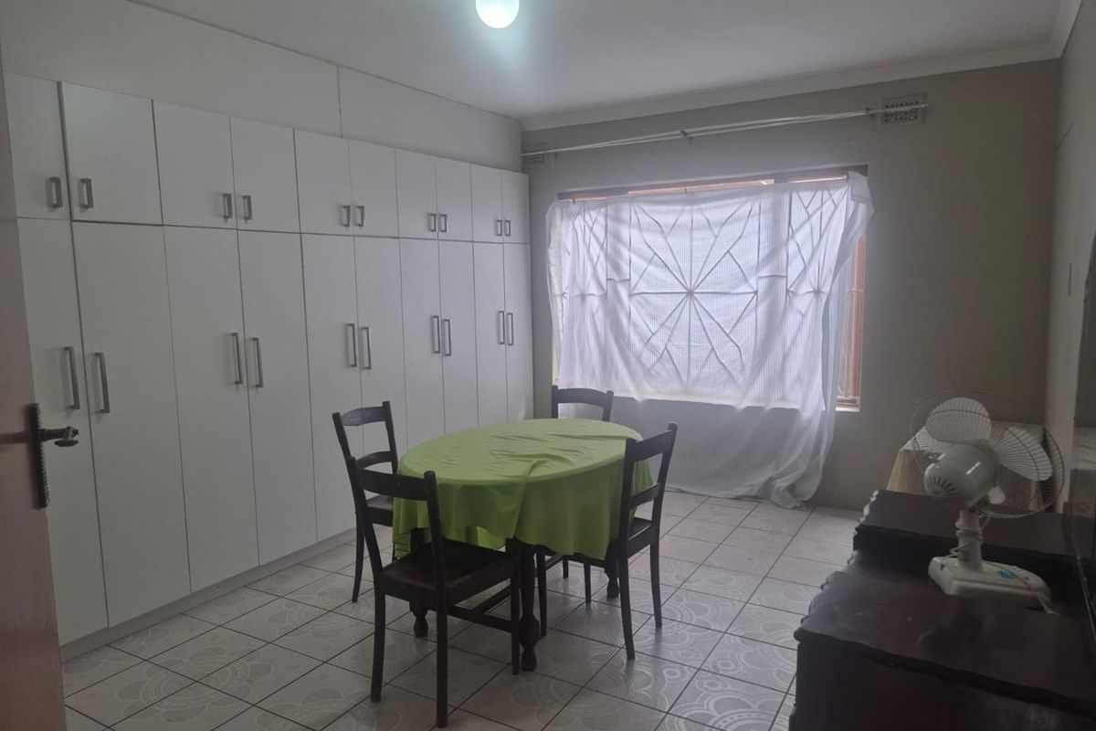 A bedroom featuring extensive floor-to-ceiling built-in cabinetry, tiled flooring, and a window with security bars.