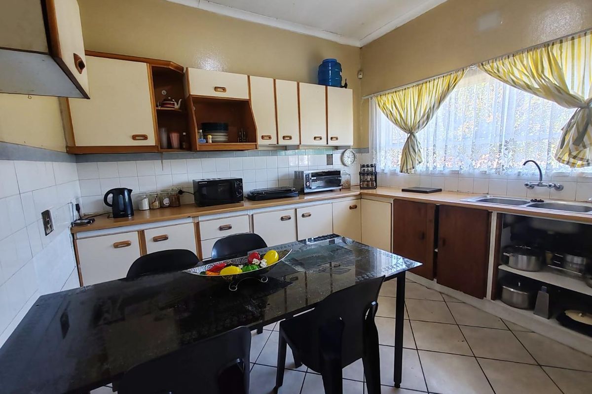 A functional kitchen featuring original cabinetry, tiled splashbacks, and a double-basin sink, offering a classic layout with potential for modern updates.