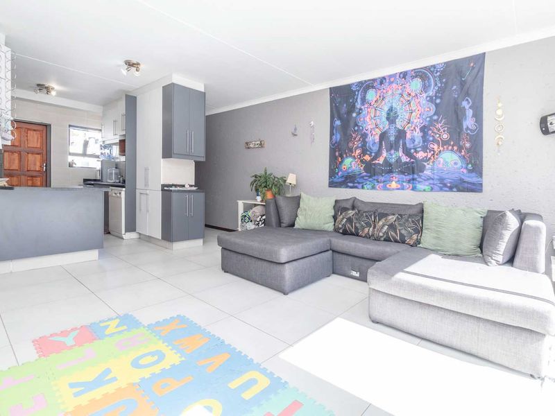 Open-plan living area featuring tiled flooring and a functional kitchen with built-in cabinetry and a breakfast counter.