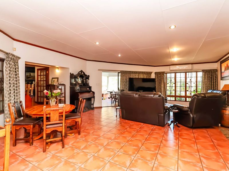 Spacious open-plan living and dining area featuring terracotta floor tiles, recessed lighting, and direct access to an outdoor patio through sliding glass doors.