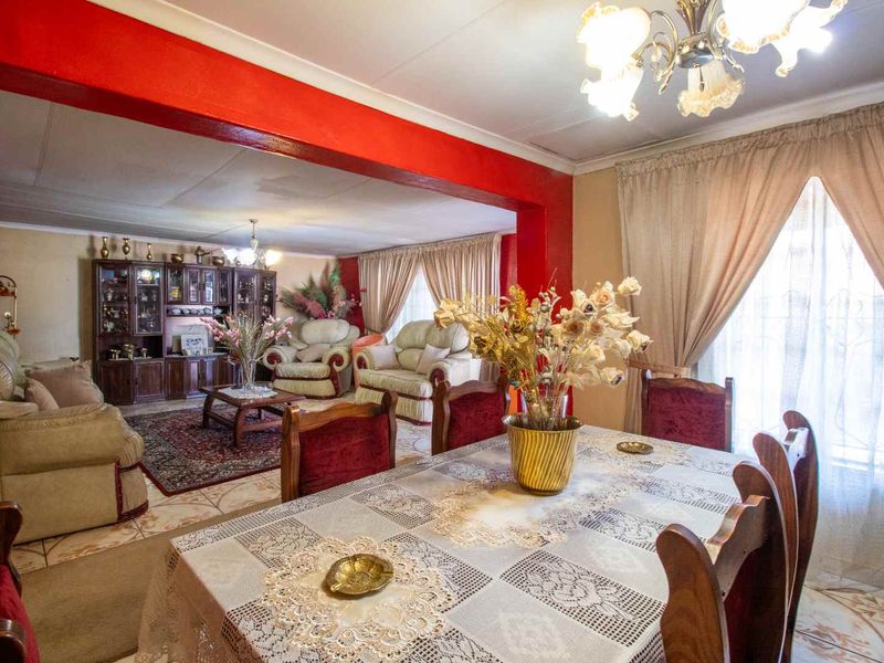 Spacious open-plan living and dining area featuring tiled flooring, a decorative archway, and classic ceiling detailing, offering a versatile layout for family living.