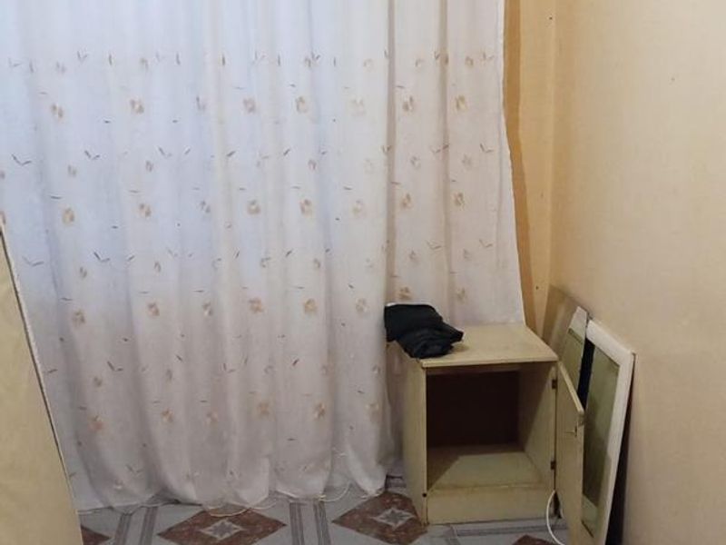 A small bedroom featuring tiled flooring and a curtain rail, currently vacant and in need of cosmetic updates to improve its overall condition.