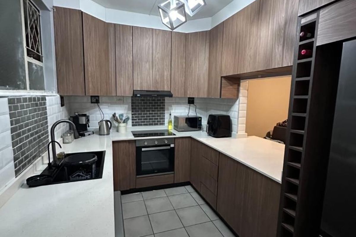 Modern kitchen featuring wood-finish cabinetry, stone countertops, subway tile backsplash, integrated wine rack, and high-quality built-in appliances.