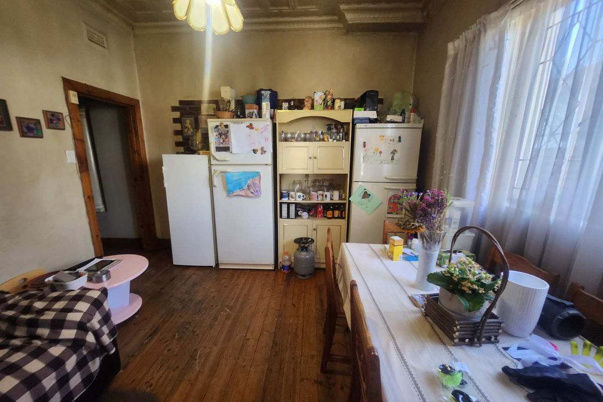 A kitchen area featuring original timber flooring and a decorative pressed metal ceiling, offering potential for renovation and modernization.