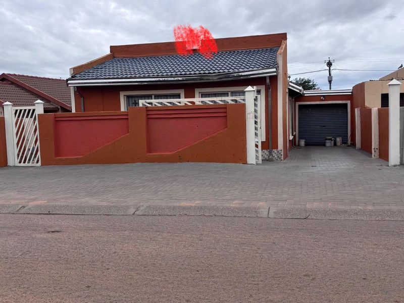 Front view of a residential property featuring a paved driveway, secure boundary wall, and a single garage.