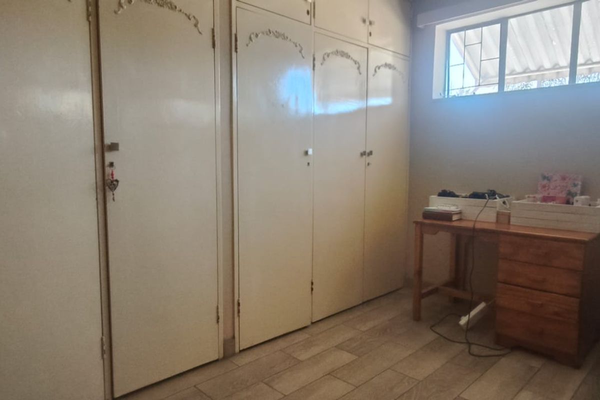 A bedroom featuring extensive built-in cupboards, high-level windows for natural light, and tiled flooring.