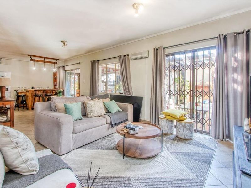 Open-plan living area featuring tiled floors, a split-system air conditioner, and sliding doors leading to an outdoor patio space.