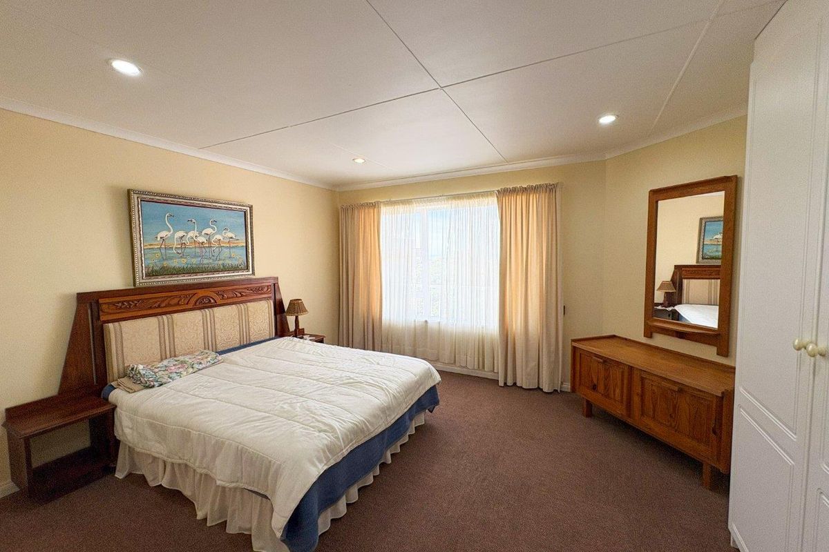 Spacious bedroom featuring neutral walls, carpeted flooring, recessed lighting, and a built-in wardrobe.