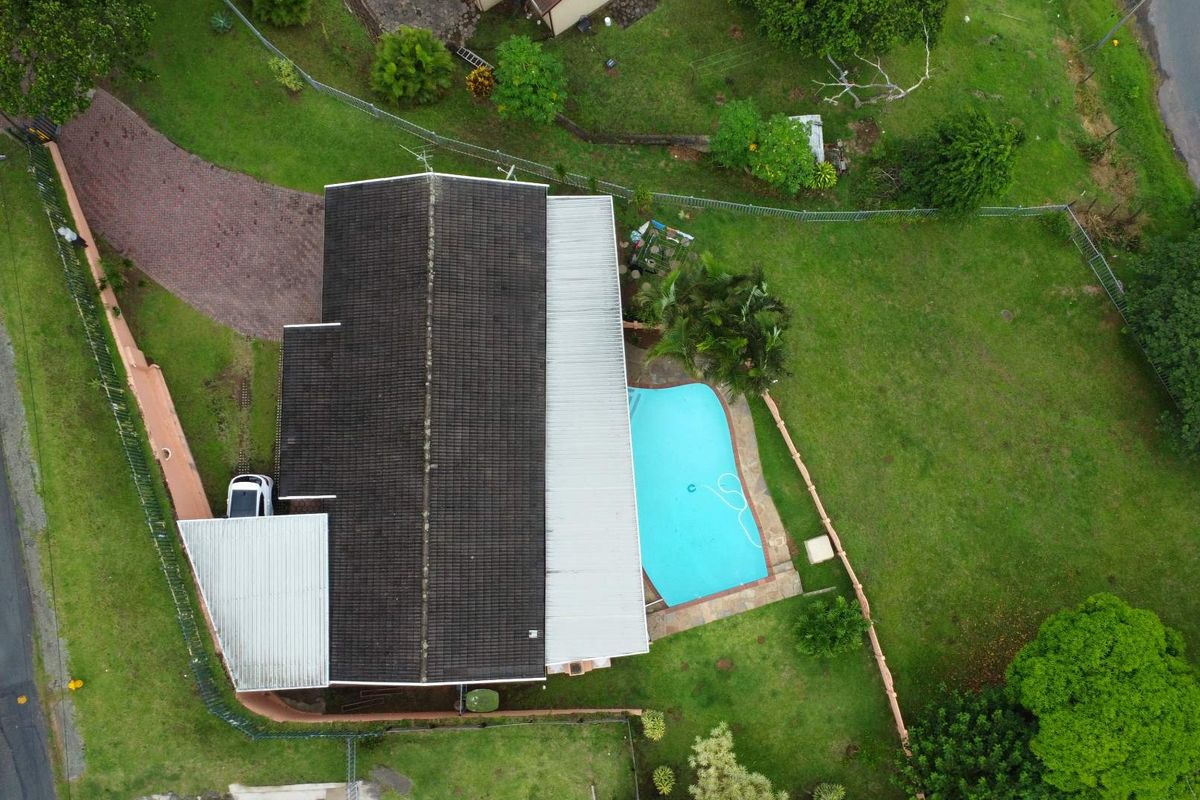 Aerial view of the property showing the main house structure, tiled roof, swimming pool, and surrounding garden area.