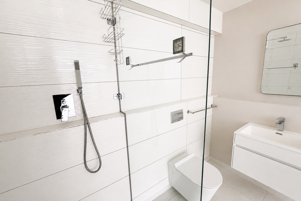 Modern bathroom featuring a wall-mounted toilet, floating vanity, and a glass-enclosed shower area with contemporary white tiled finishes.