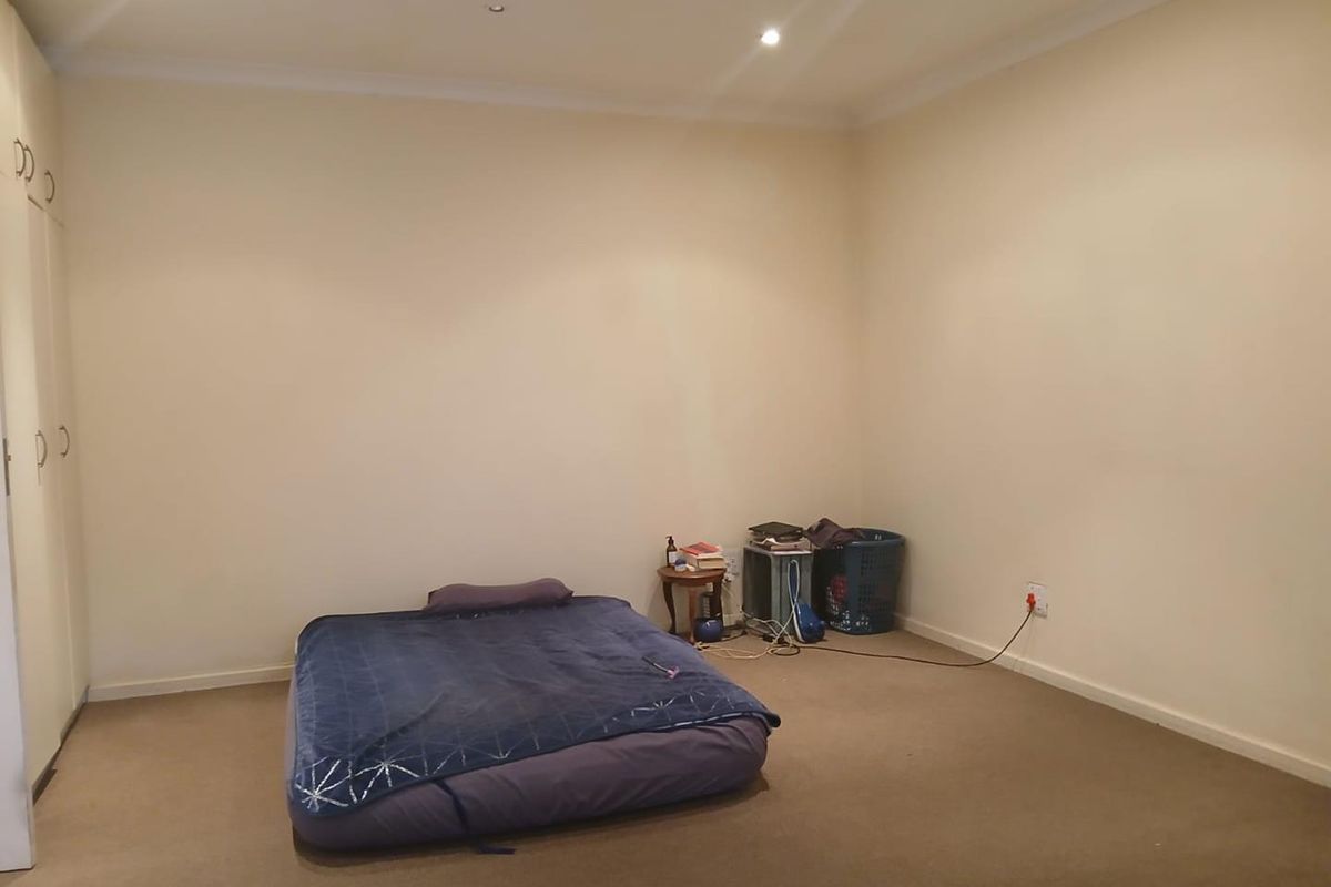 A spacious bedroom featuring neutral walls, carpeted flooring, built-in cupboards, and recessed downlighting, offering a blank canvas for personalization.