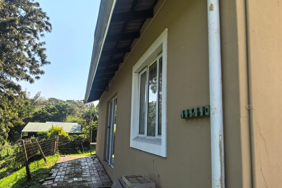 Rear exterior view of the townhouse featuring a paved walkway, sliding door access, and visible wear on the exterior wall and downpipe.
