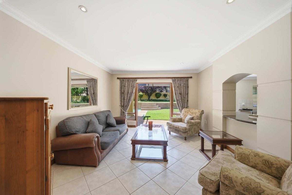 Spacious living room featuring tiled flooring, recessed lighting, and direct access to the rear garden through sliding glass doors.