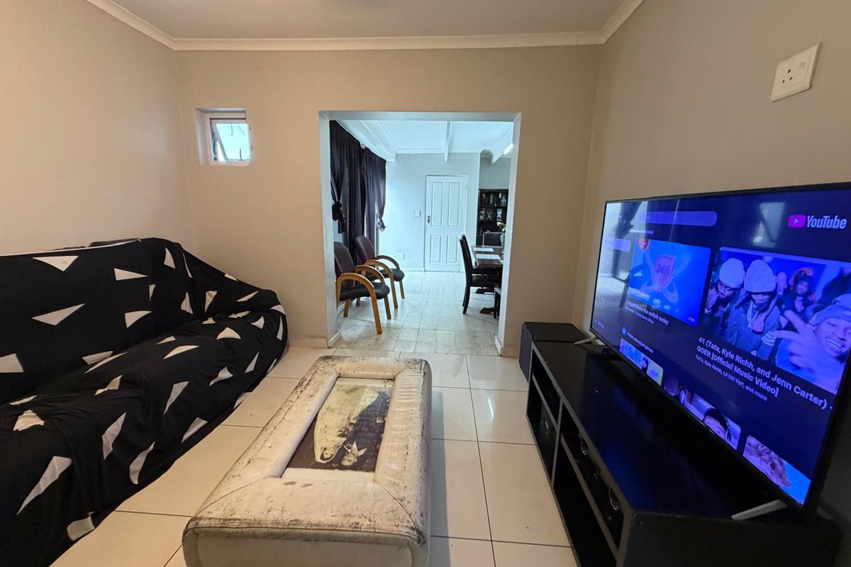 A living room featuring tiled flooring and a wide opening leading to an adjacent dining area.