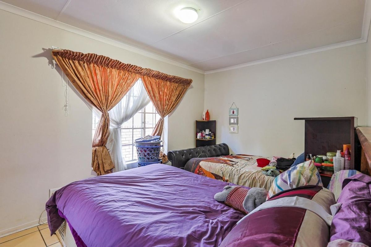 A bedroom featuring tiled flooring, a window with security bars, and a ceiling-mounted light fixture.