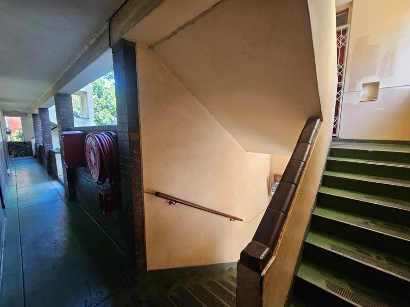 Communal apartment hallway and staircase area featuring brick detailing, a fire hose reel, and painted stair treads.