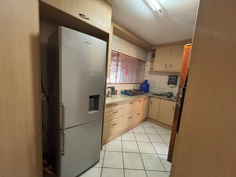 A functional kitchen featuring laminate cabinetry, granite countertops, tiled flooring, and a tiled backsplash, offering a practical layout for daily meal preparation.