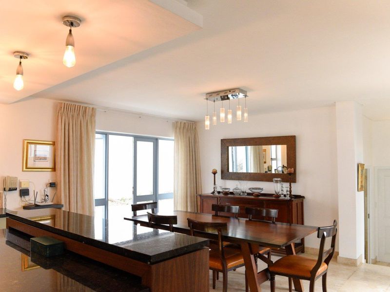 Spacious open-plan living and dining area featuring a granite kitchen island, tiled flooring, and large sliding glass doors providing ample natural light.