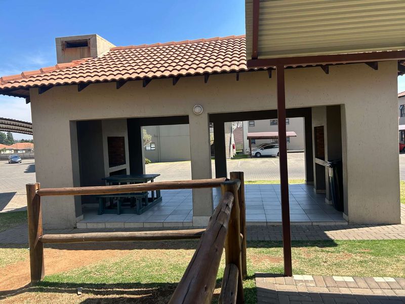A covered outdoor patio area featuring tiled flooring, masonry pillars, and built-in braai facilities, suitable for outdoor entertaining.