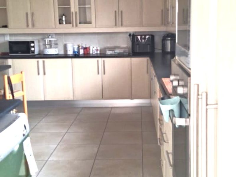 A functional kitchen featuring light-toned built-in cabinetry, tiled flooring, and integrated appliances including an oven and microwave.