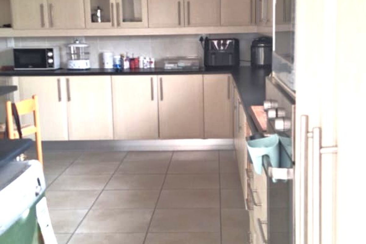 A functional kitchen featuring light-toned built-in cabinetry, tiled flooring, and integrated appliances including an oven and microwave.