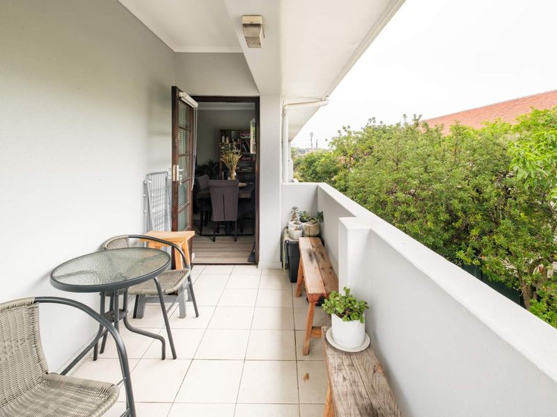 A covered balcony featuring tiled flooring and a solid balustrade, providing an outdoor extension to the interior living space.