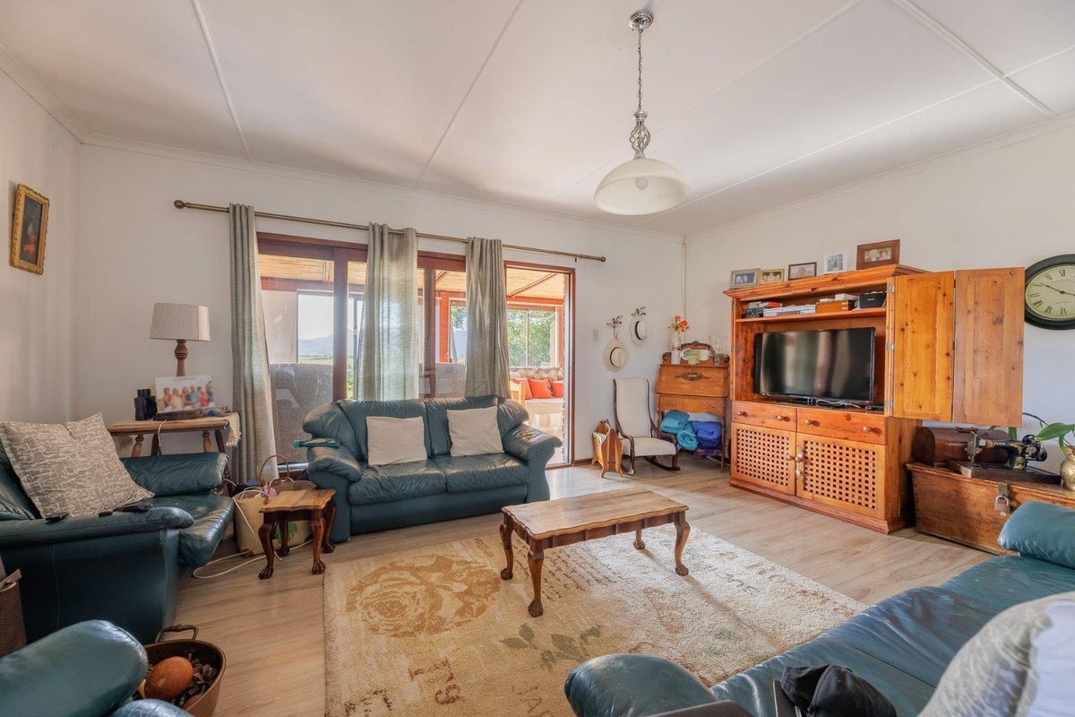A comfortable living room featuring light wood-look flooring, a central pendant light, and sliding glass doors that open onto a covered patio area.