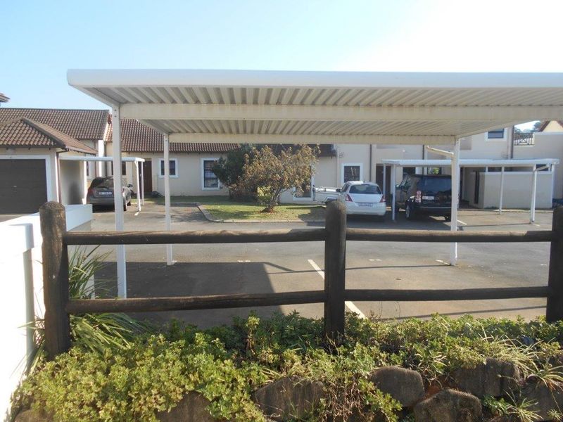 Exterior view of the apartment complex featuring covered parking bays and a timber fence boundary.