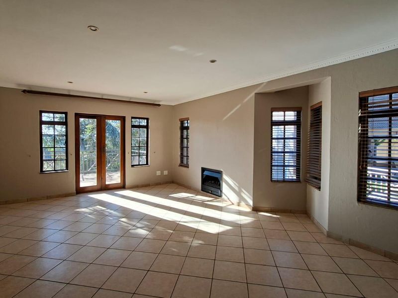 Spacious living room featuring tiled flooring, a built-in fireplace, and french doors leading to an outdoor area, providing ample natural light.