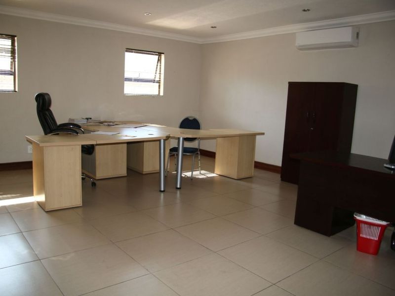 A functional office space featuring tiled flooring, recessed downlighting, and a wall-mounted air conditioning unit.