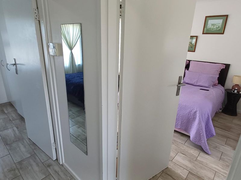 A view from a tiled hallway looking into a bedroom, featuring neutral wall finishes and standard internal door fixtures.