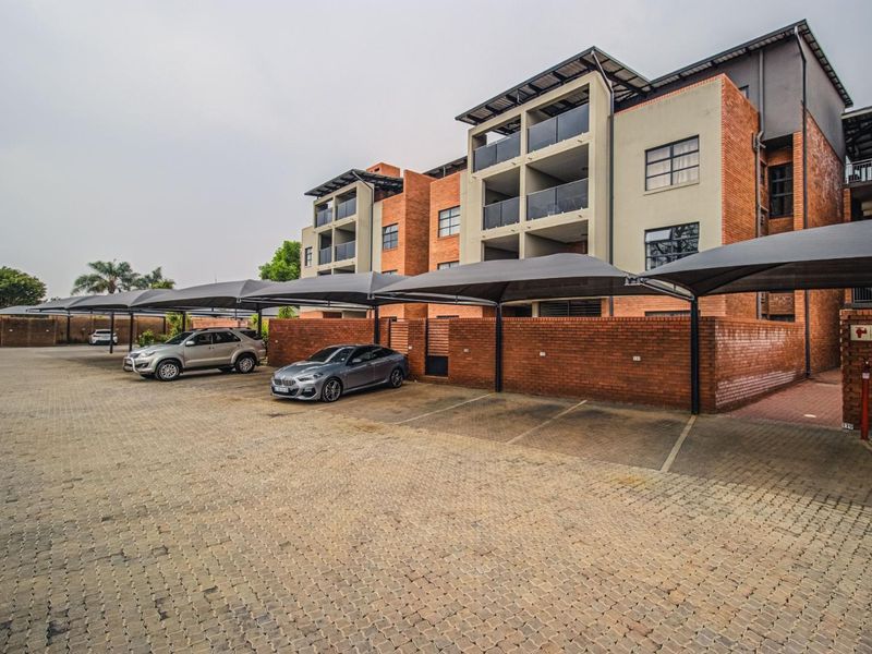 Exterior view of a multi-story townhouse complex featuring brick facade architecture, private balconies, and dedicated covered parking bays.