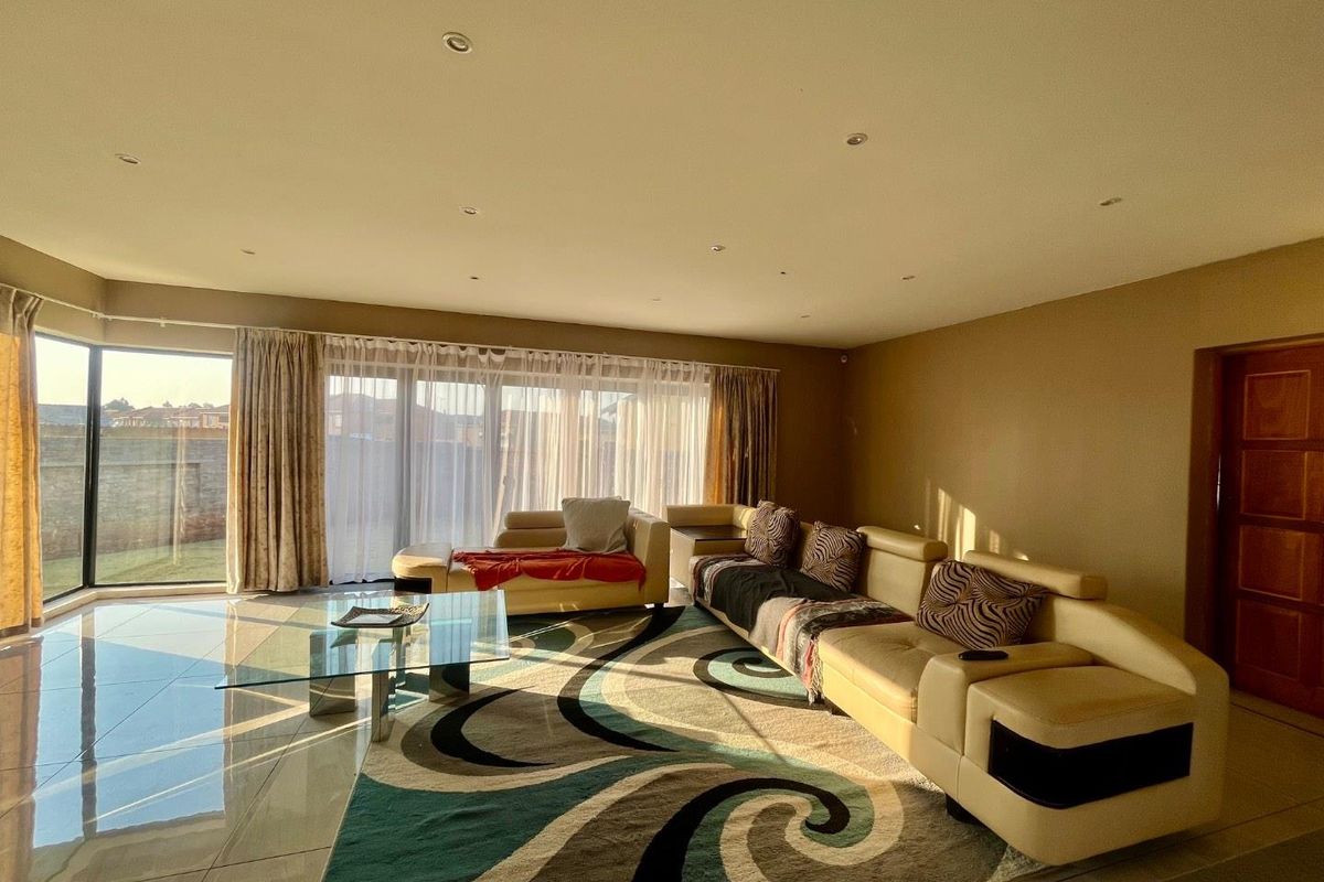 Spacious living room featuring large format floor tiles, recessed downlighting, and expansive sliding glass doors providing natural light and garden access.