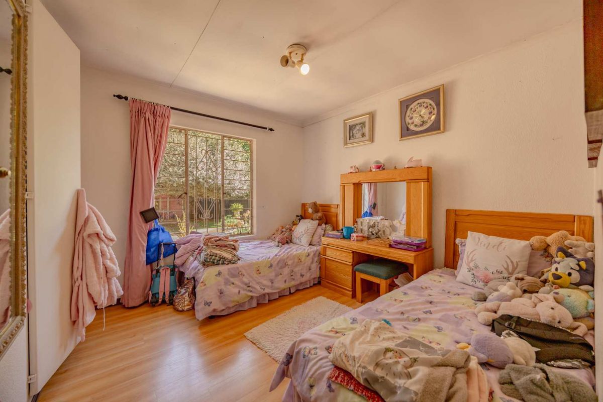 A functional bedroom featuring laminate flooring, a built-in wardrobe, and a window fitted with a security gate.