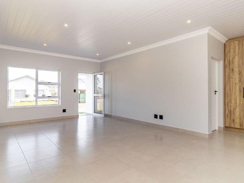 Spacious open-plan living area featuring neutral tiled floors, recessed lighting, and a modern tongue and groove ceiling with integrated cabinetry.