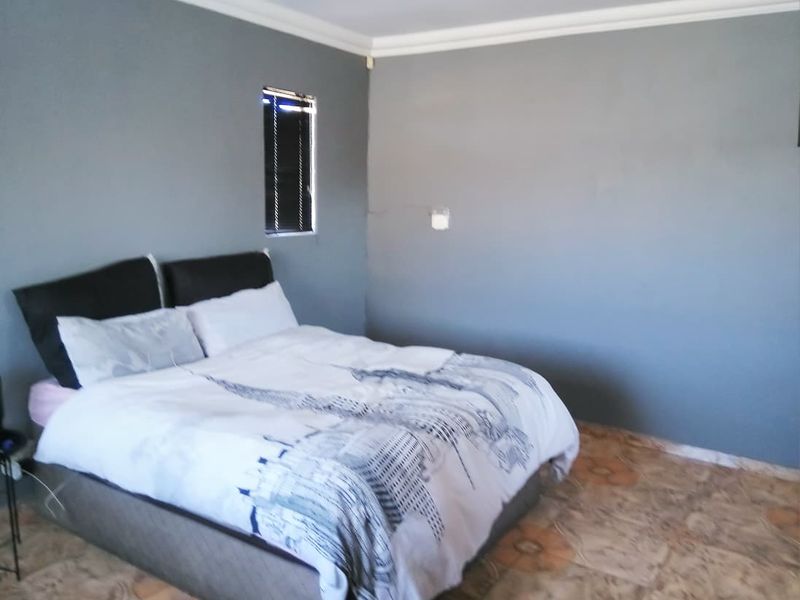 A bedroom featuring grey painted walls, crown molding, and tiled flooring with a visible hairline crack on the wall.