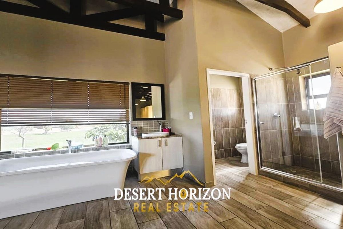 Spacious bathroom featuring a freestanding bathtub, a separate glass-enclosed shower, a vanity unit, and a private toilet area with tiled flooring.
