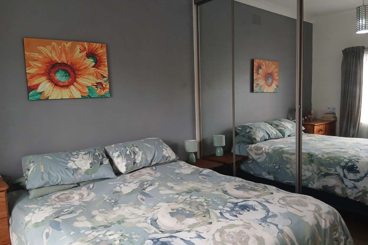 A bedroom featuring a large built-in wardrobe with mirrored sliding doors and a dark grey feature wall.