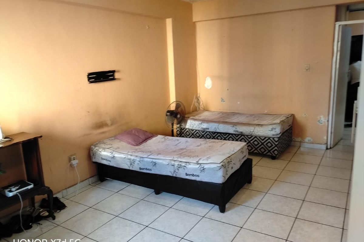 A bedroom featuring ceramic tiled flooring and plain walls requiring maintenance and cosmetic updates to improve the overall condition of the space.