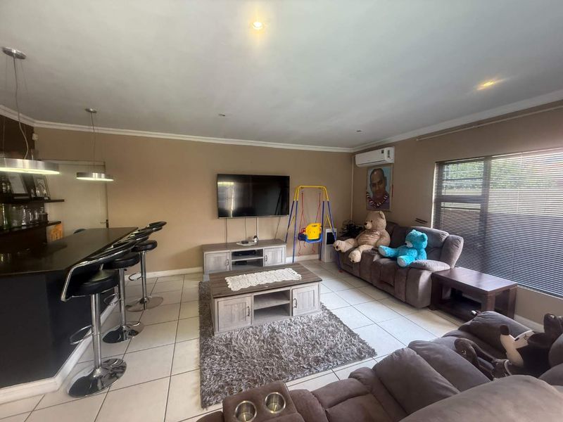 Open-plan living area featuring tiled flooring, a breakfast bar, and a split-system air conditioner, providing a functional space for relaxation and dining.