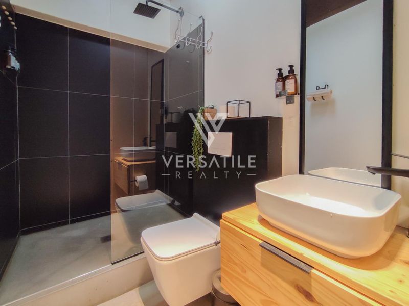 Modern bathroom featuring a walk-in shower with glass screen, wall-mounted toilet, and a floating vanity with a vessel sink.