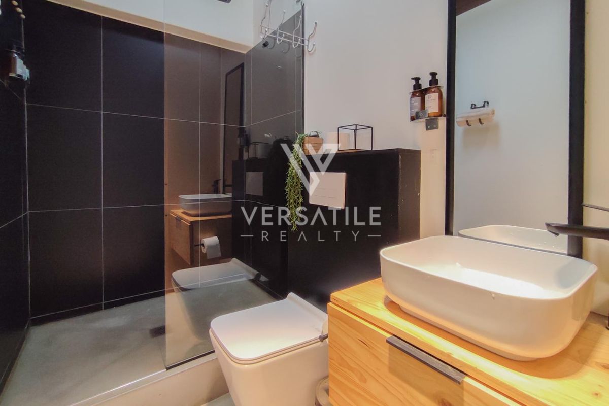 Modern bathroom featuring a walk-in shower with glass screen, wall-mounted toilet, and a floating vanity with a vessel sink.