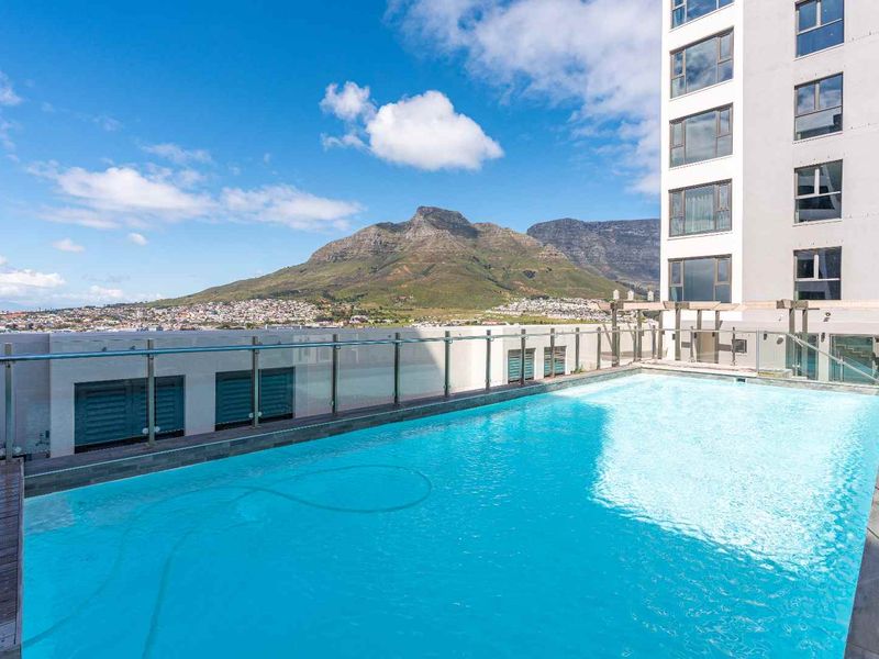 A pristine rooftop swimming pool featuring modern glass balustrades and timber decking, offering stunning mountain views.